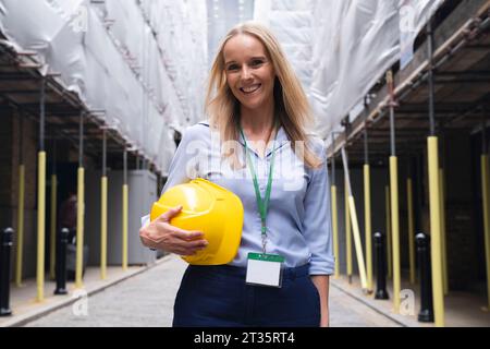 Smiling engineer holding hardhat standing at construction site Stock Photo