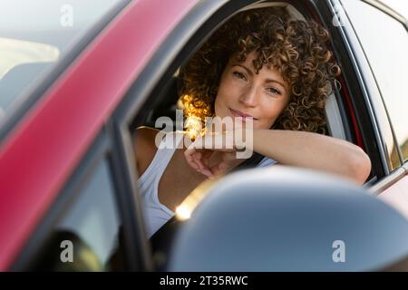 Woman with curly hair sitting in car Stock Photo
