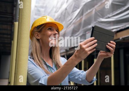 Happy engineer holding tablet PC at construction site Stock Photo