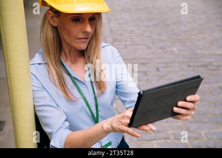 Focused engineer using tablet PC leaning on pole Stock Photo