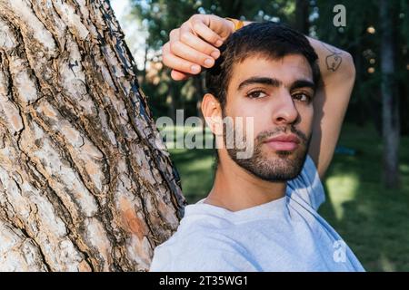 Thoughtful man leaning on tree Stock Photo