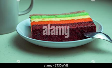 Rainbow cake, purple red yellow green served on a plate Stock Photo