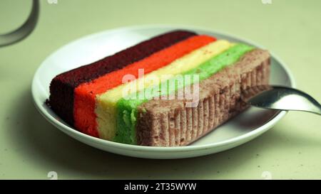 Rainbow cake, purple red yellow green served on a plate Stock Photo