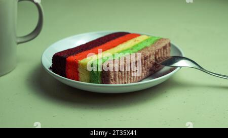Rainbow cake, purple red yellow green served on a plate Stock Photo