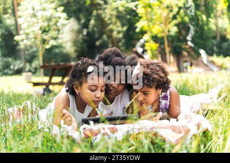 Curious sisters spending leisure time and using tablet PC in garden Stock Photo
