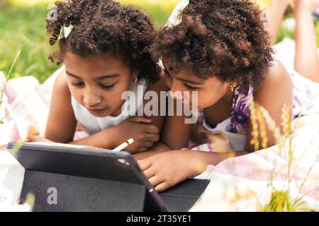 Curious twin sisters using tablet PC in garden Stock Photo