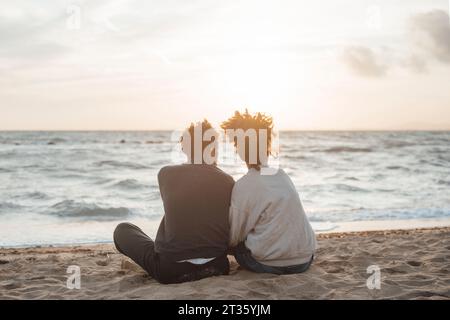 Loving couple sitting on sand at beach Stock Photo