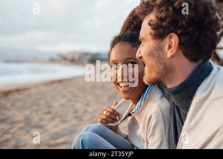 Cheerful couple spending leisure time sitting at beach Stock Photo