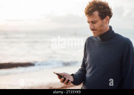 Man using smart phone at beach Stock Photo