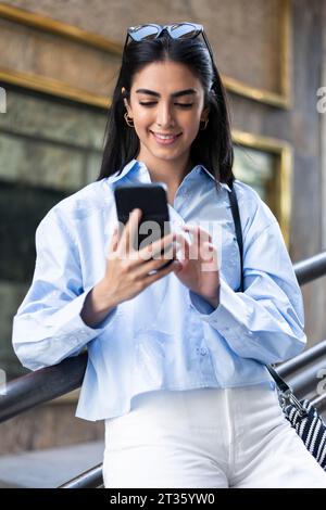 Smiling young woman using smart phone Stock Photo
