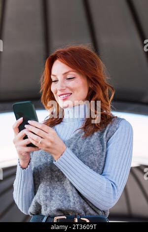 Happy redhead woman using mobile phone Stock Photo
