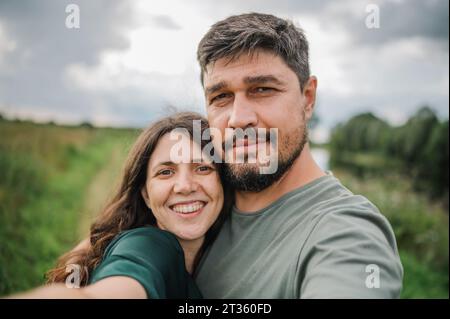 Smiling woman taking selfie with man Stock Photo