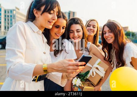 Happy woman using smart phone with friends Stock Photo
