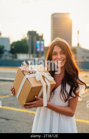 Happy woman holding gift box at sunset Stock Photo