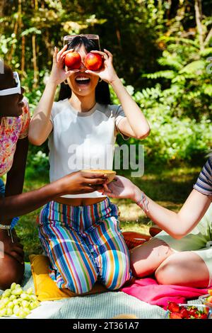 Smiling woman holding apples over eyes in garden Stock Photo