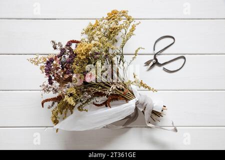 Bouquet of dried flowers lying on white painted wood Stock Photo