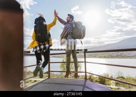 Couple jumping and giving high-five at observation point Stock Photo