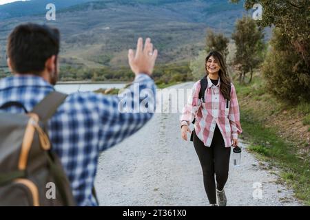 Man waving woman walking on footpath Stock Photo