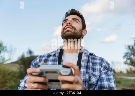Man looking up holding drone controller Stock Photo