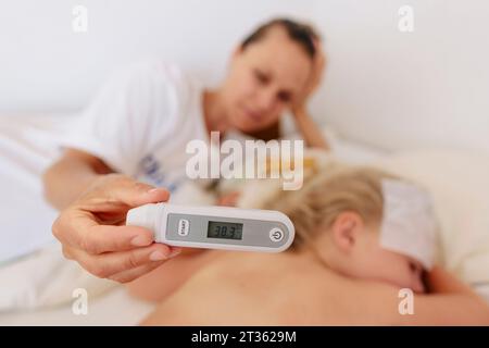 Mother showing body temperature of daughter on thermometer Stock Photo