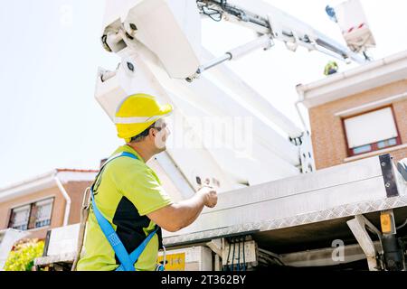Engineer showing thumbs up gesture standing in front of hydraulic platform Stock Photo