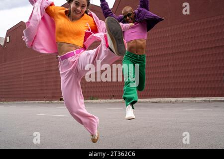 Cheerful couple jumping and having fun together in front of building Stock Photo