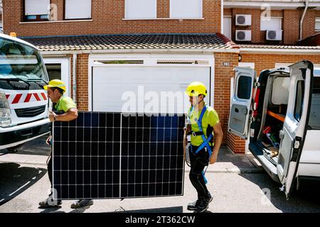 Engineers walking with solar panel on sunny day Stock Photo