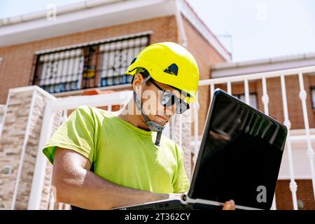 Engineer wearing hardhat working on laptop Stock Photo