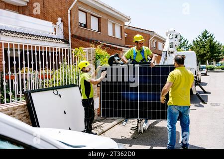 Engineers holding solar panel and standing on road Stock Photo