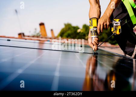 Hands of engineer with drill machine installing solar panels Stock Photo