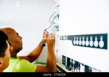 Engineer with colleague installing system in utility room Stock Photo