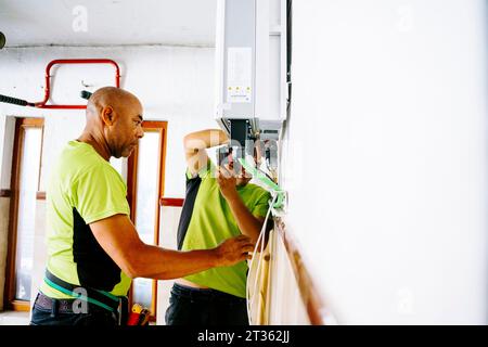 Engineer with colleague using drill machine Stock Photo