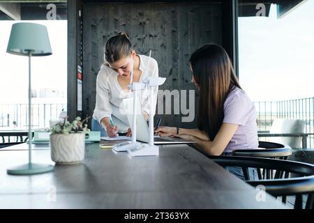 Two young female engineers working at desk on sustainable energy project Stock Photo