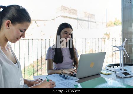 Two young female engineers working at desk using laptop Stock Photo