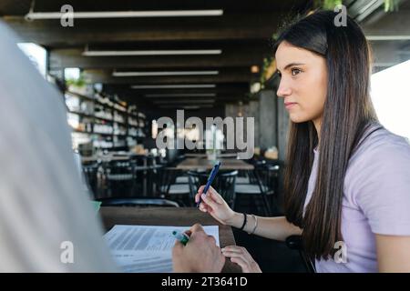 Portrait of pretty brunette working on documents at coworking space Stock Photo