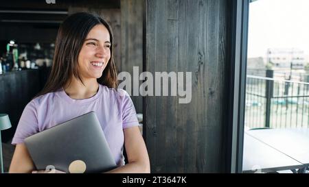 Portrait of beautiful brunette woman holding laptop Stock Photo