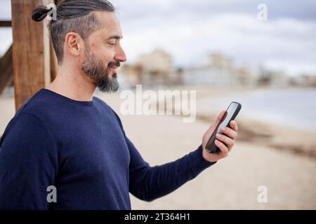 Mature man using smart phone at beach Stock Photo