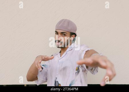 Young man gesturing in front of wall Stock Photo