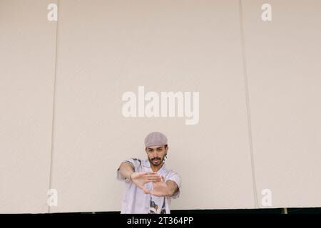 Young man wearing beret cap gesturing in front of wall Stock Photo