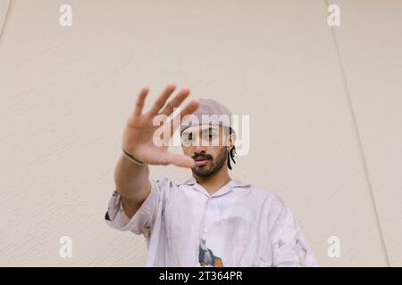 Young man showing stop gesture in front of wall Stock Photo