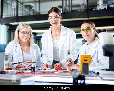 Smiling engineers with electronic work tools in laboratory Stock Photo