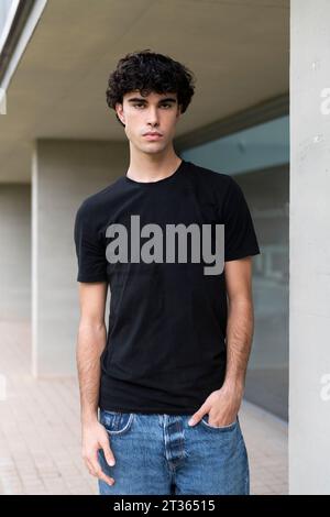 Serious young man with hand in pocket standing near building Stock Photo
