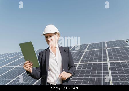 Smiling engineer using tablet PC in front of solar panels Stock Photo