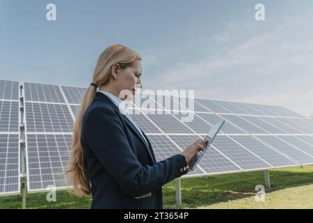 Engineer using tablet PC in front of solar panels Stock Photo