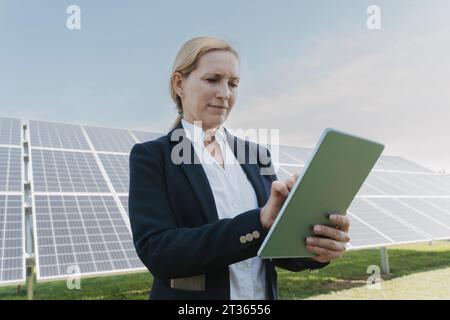 Mature engineer using tablet PC in front of solar panels Stock Photo