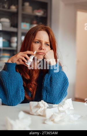 Sad sick woman sitting with medicine and tissue papers at table Stock Photo