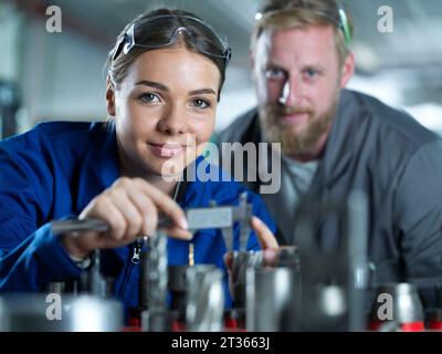 Industry worker with trainee measuring CNC tool in factory Stock Photo