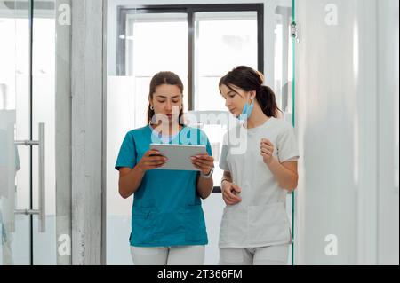 Dentist using tablet PC by colleague in clinic Stock Photo