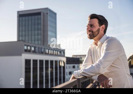 Smiling businessman leaning on railing Stock Photo