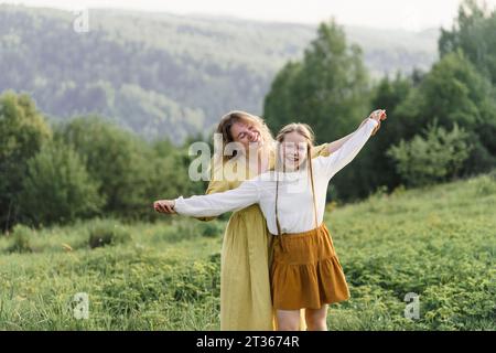 Happy mother and daughter spending leisure time in meadow Stock Photo